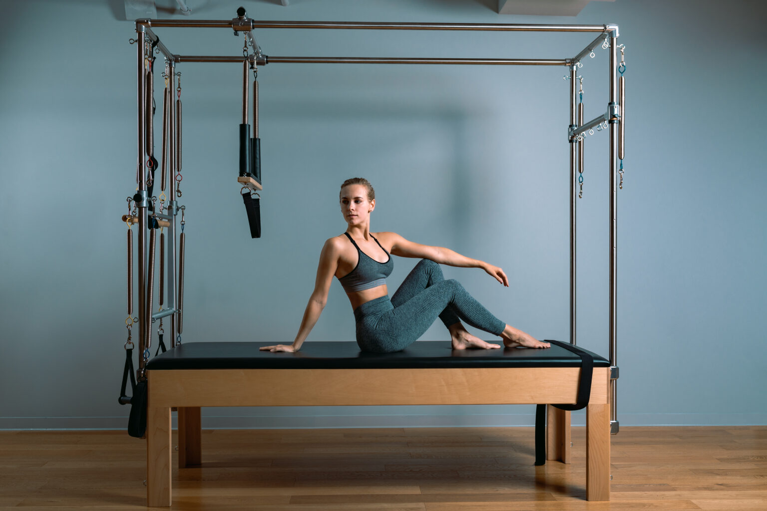 Pilates woman in a Cadillac reformer doing stretching exercises in the gym. Fitness concept, special fitness equipment, healthy lifestyle, plastic. Copy space, sport banner for advertising.